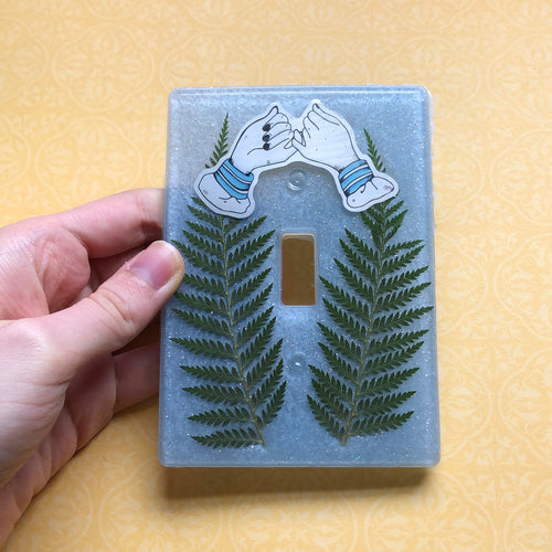 Glittery blue outlet cover with dried ferns